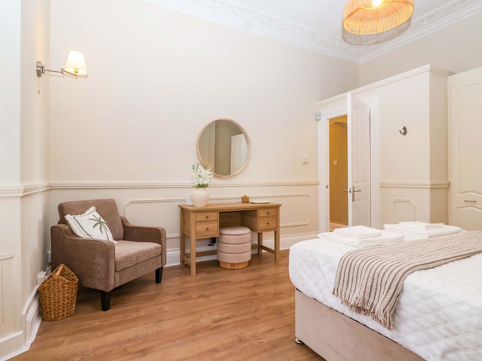 A bedroom with a chair, table, and bed at Flat 2 The Moorings Torquay