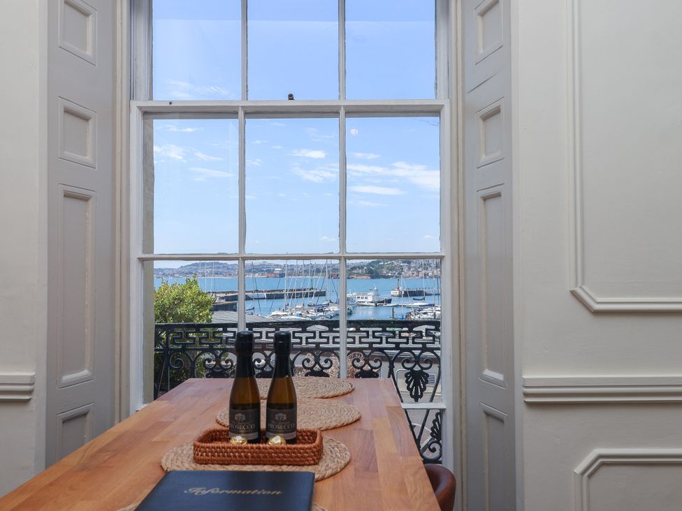 A dining room with table and bottles overlooking a harbor at Flat 2 The Moorings Torquay