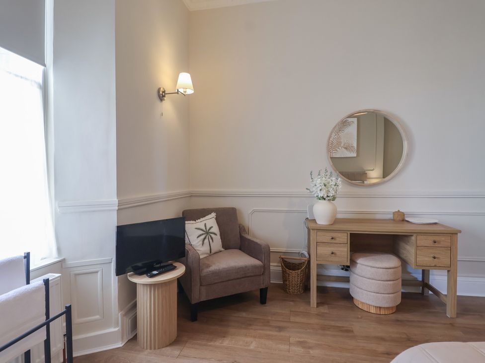 A living room with a chair, desk, and television at Flat 2 The Moorings in Torquay