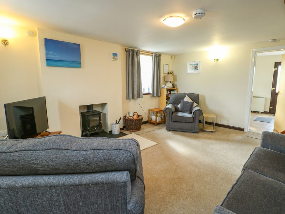 A living room with a fireplace and seating at Getws in Ty Croes