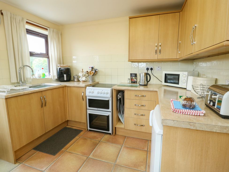 A kitchen with cabinets, oven, sink and appliances at Getws in Ty Croes