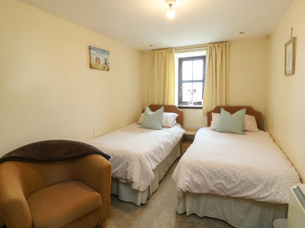 A bedroom with two beds and a chair at Getws Ty Croes