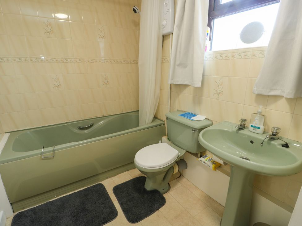 A bathroom with a bathtub, toilet, and sink at Getws Ty Croes