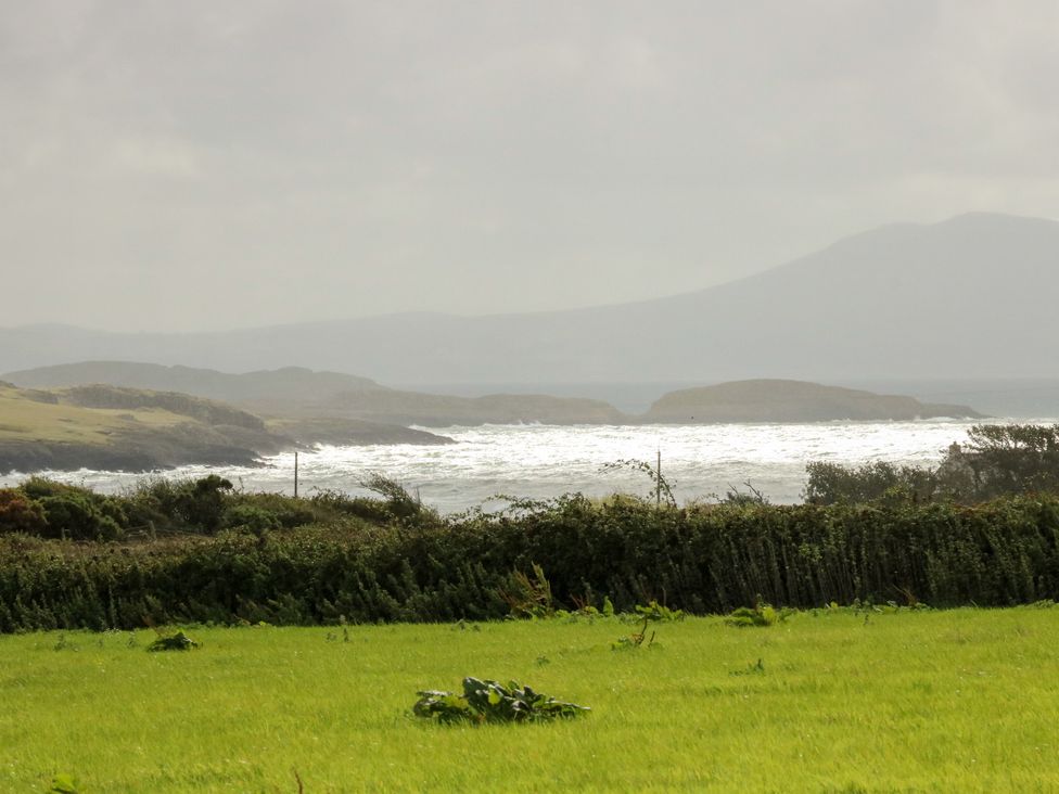 An ocean view with waves and hills at Getws in Ty Croes