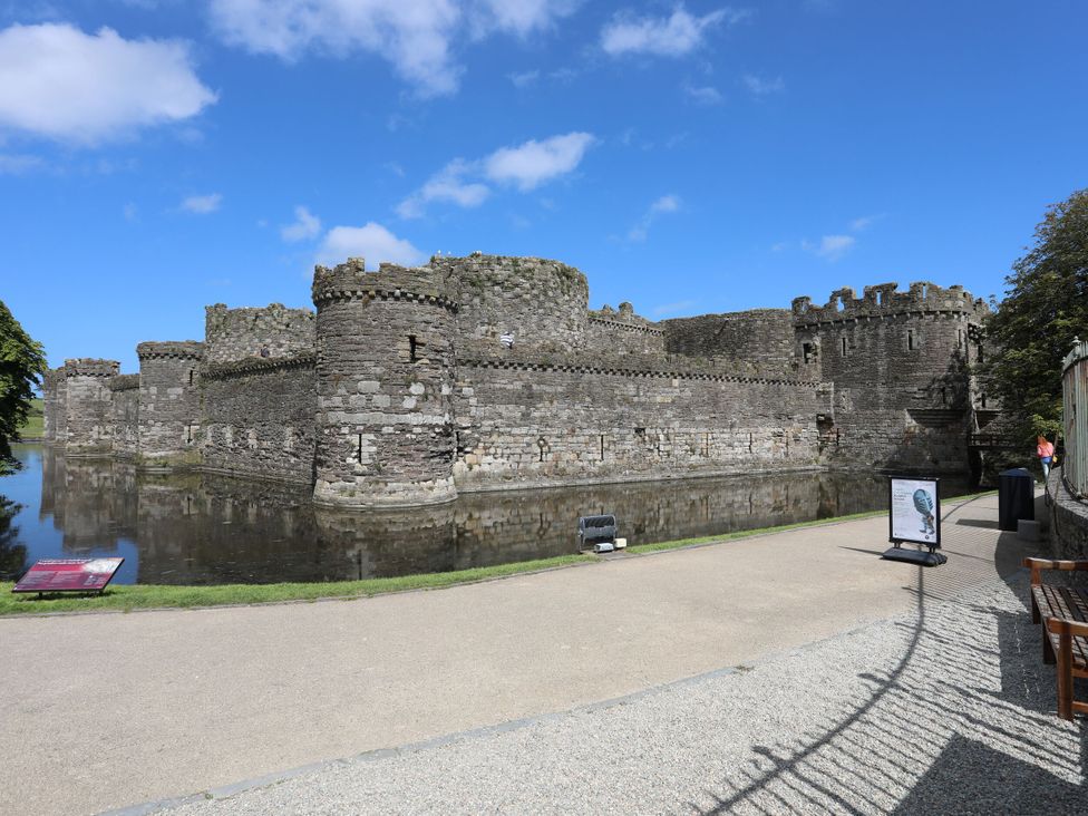 A castle surrounded by water with a pathway and benches at 15 Rose Hill Beaumaris