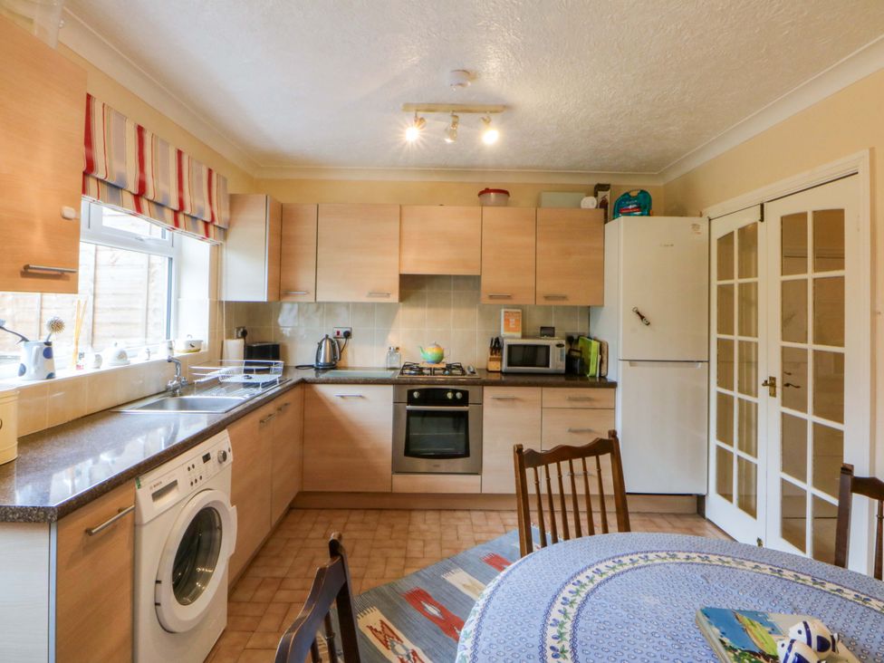 A kitchen with cabinets, appliances and dining table at 15 Rose Hill Beaumaris