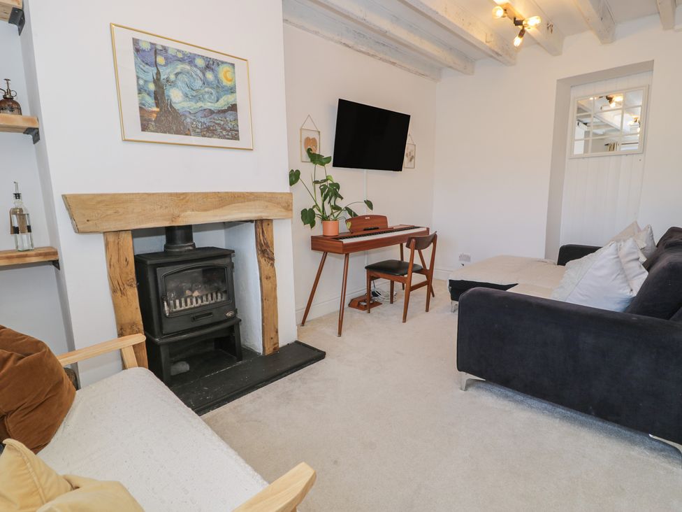 A living room with a fireplace and a television at Lon Popty in Dolgellau