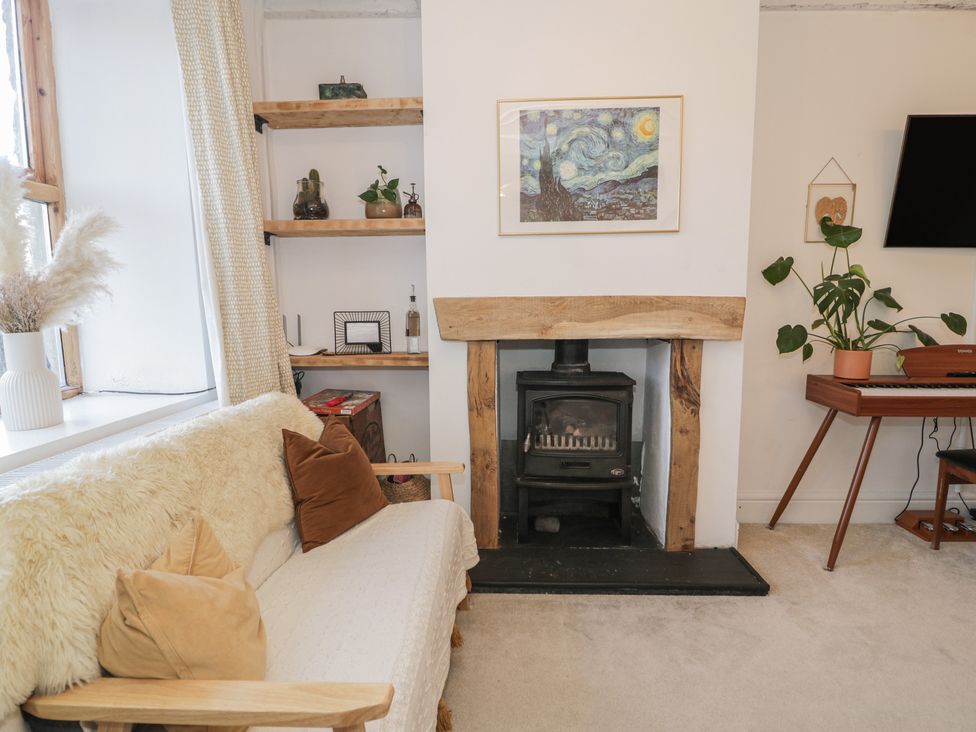 A living room with a fireplace and sofa at Lon Popty in Dolgellau