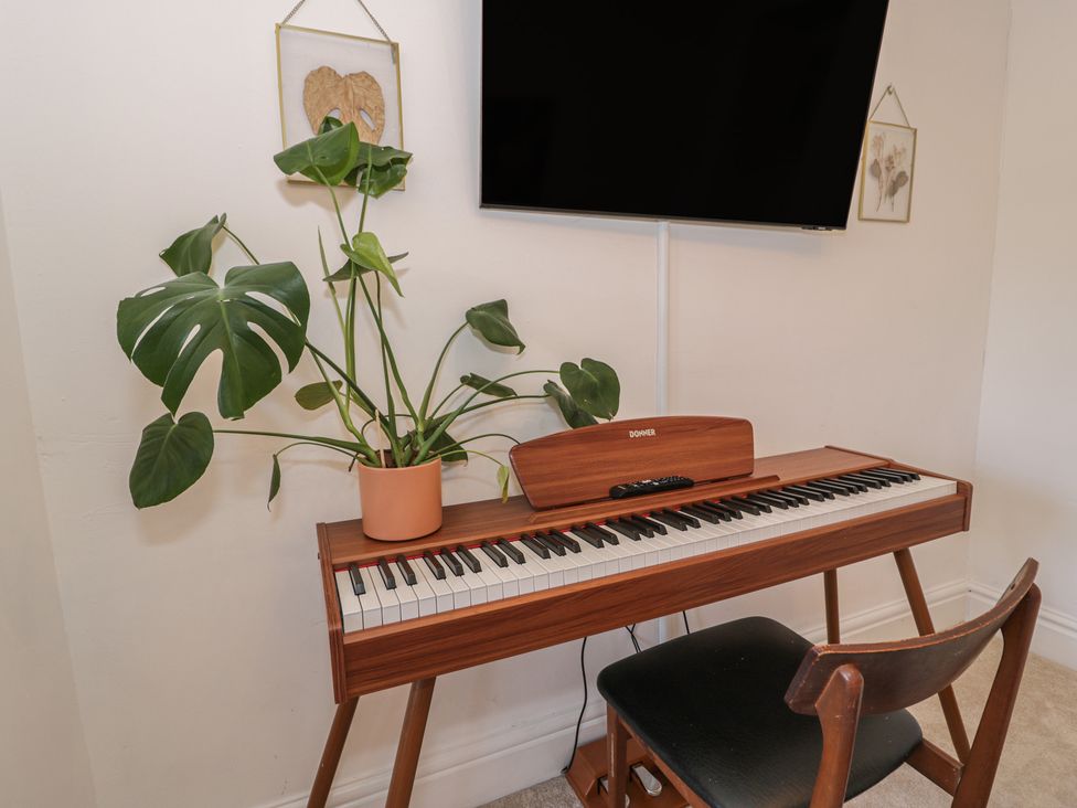 A piano and plant in a living room at Lon Popty in Dolgellau