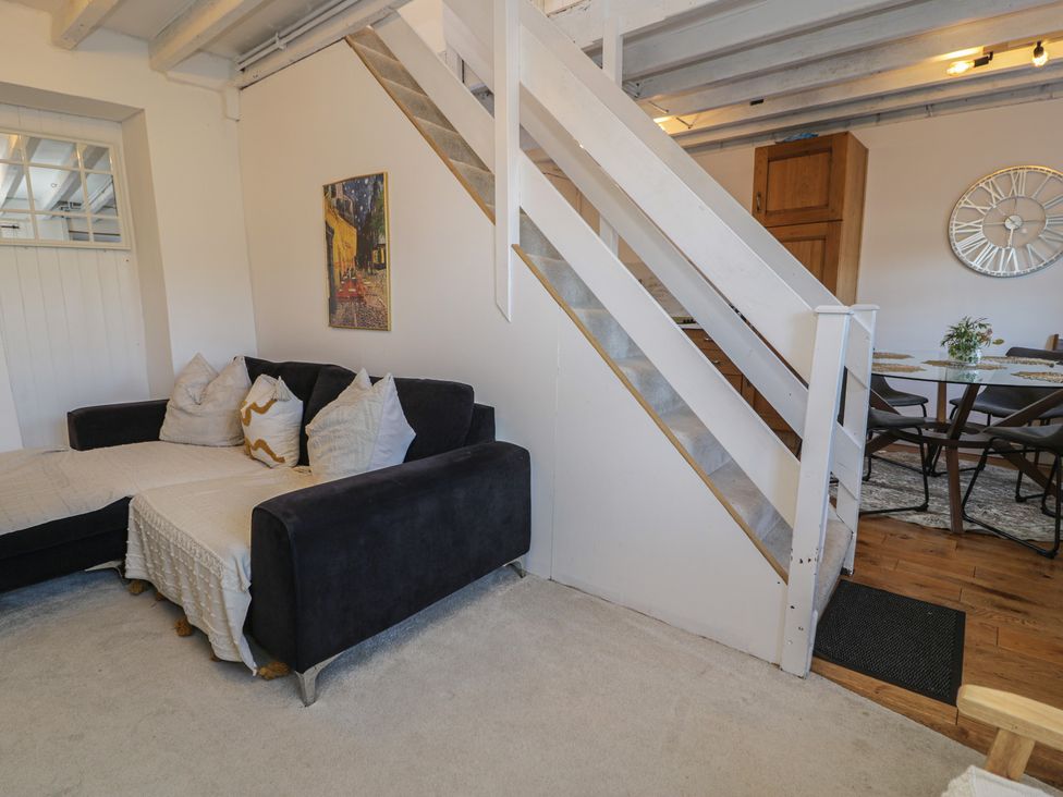 A living room with a sofa and stairs at Lon Popty in Dolgellau