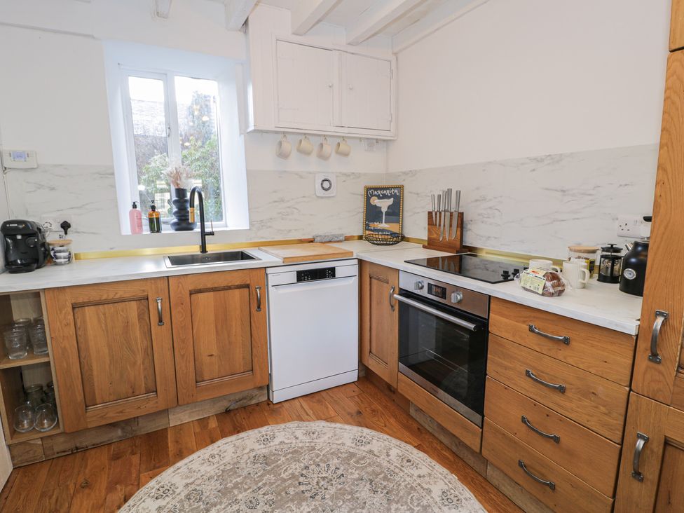 A kitchen with wooden cabinets and appliances at Lon Popty in Dolgellau