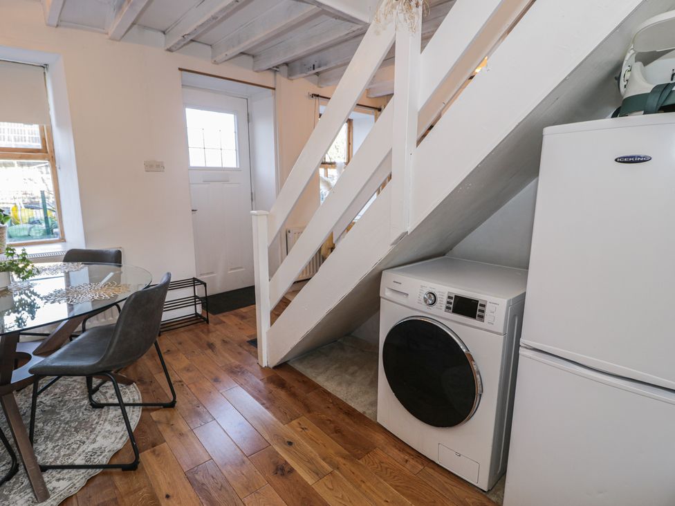 A dining room with a washing machine and refrigerator at Lon Popty in Dolgellau