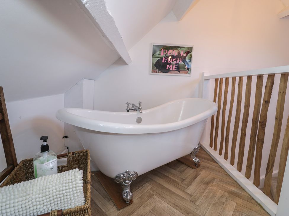 A bathroom with a freestanding bathtub and a picture at Lon Popty Dolgellau