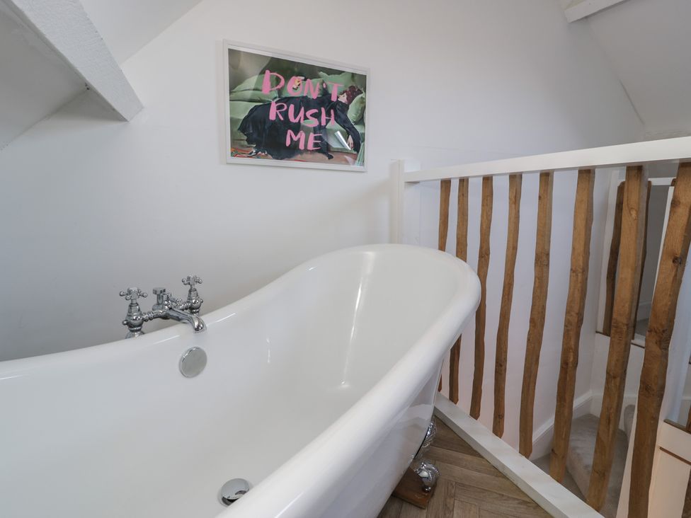 A bathroom with a bath tub and a framed artwork at Lon Popty in Dolgellau