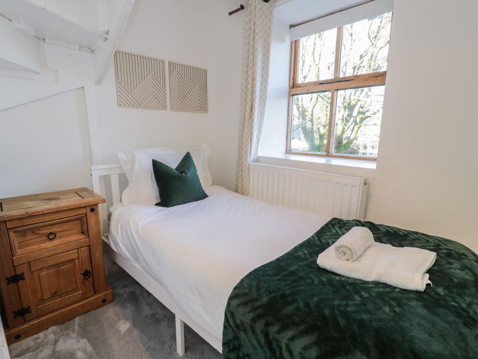 A bedroom with a bed and nightstand at Lon Popty Dolgellau