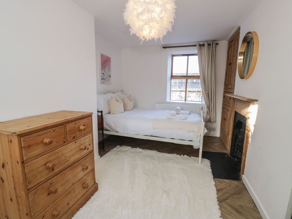 A bedroom with a bed and a dresser at Lon Popty in Dolgellau