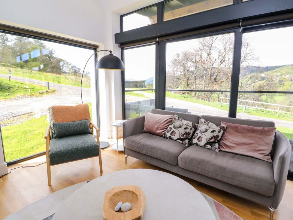 A living room with a sofa and chair by large windows at Strathview