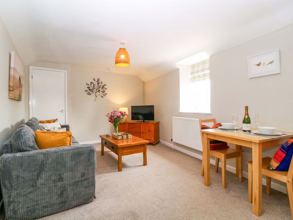 A living room with a sofa, coffee table and dining area at Farm View Annex in Painswick