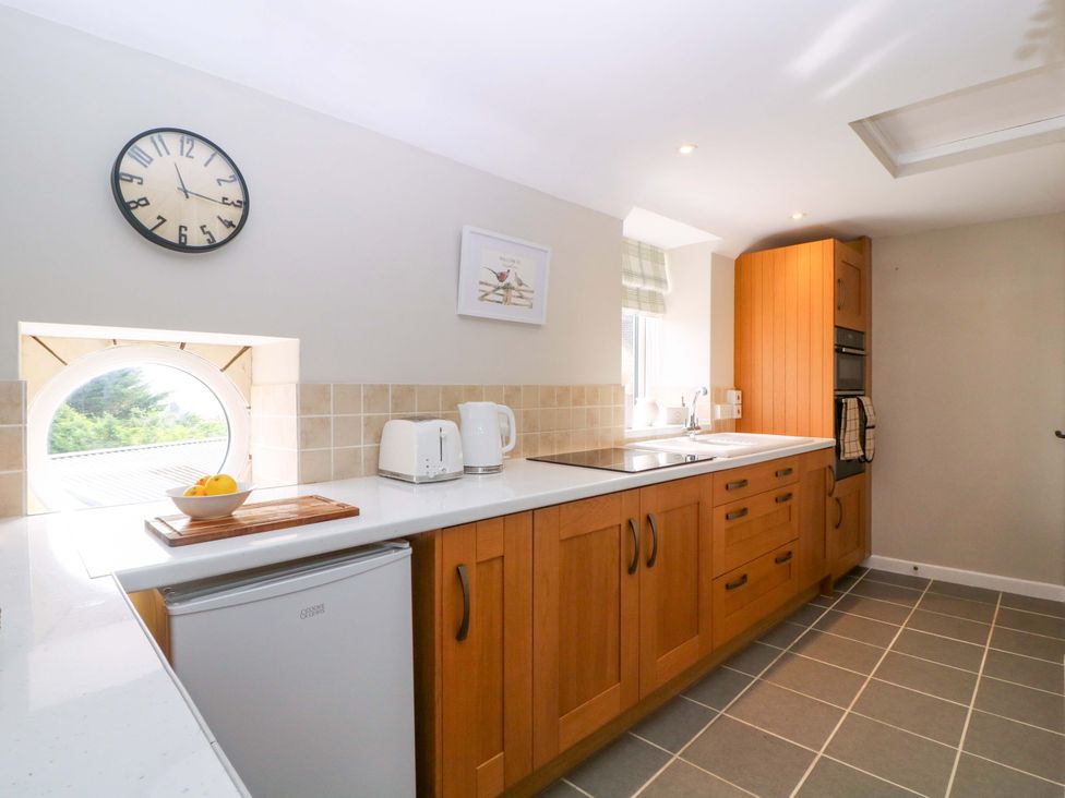 A kitchen with wooden cabinets and appliances at Farm View Annex in Painswick
