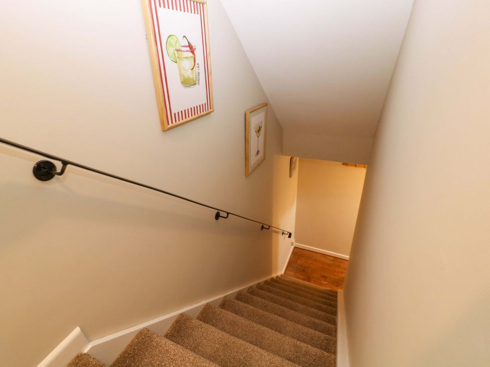 A staircase with a handrail and paintings on the wall at Farm View Annex in Painswick