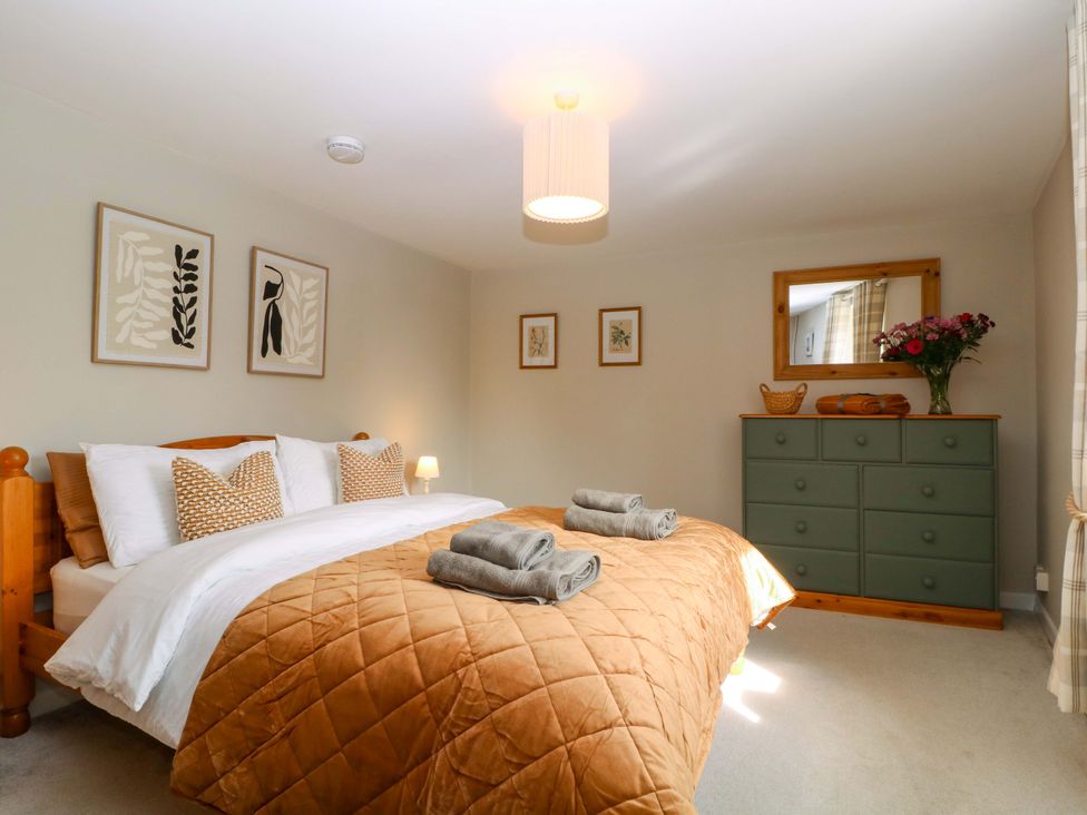 A bedroom with a bed, dresser, and wall art at Farm View Annex in Painswick