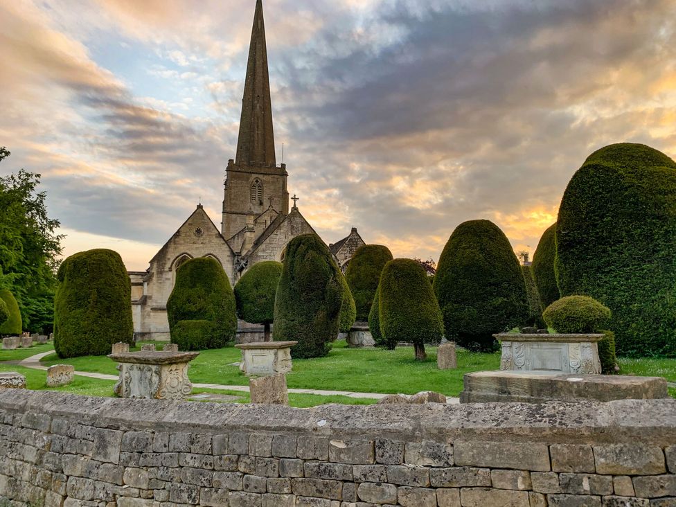 A church with a spire and topiary in the outdoor area at Farm View Annex in Painswick