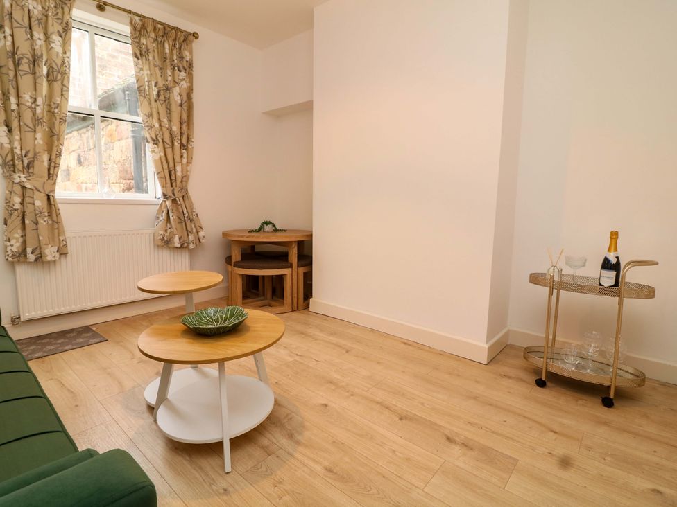 A living room with a sofa, coffee tables, and a champagne bottle at 14 Crown terrace in Belper