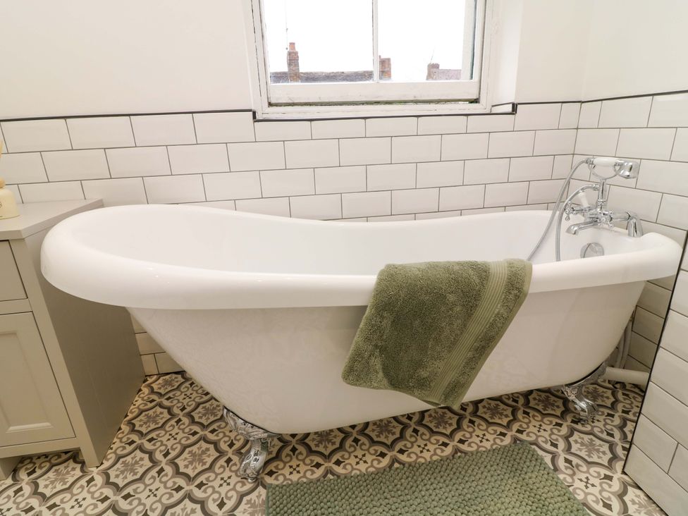 A bathtub with a towel and sink in the bathroom at 14 Crown terrace Belper