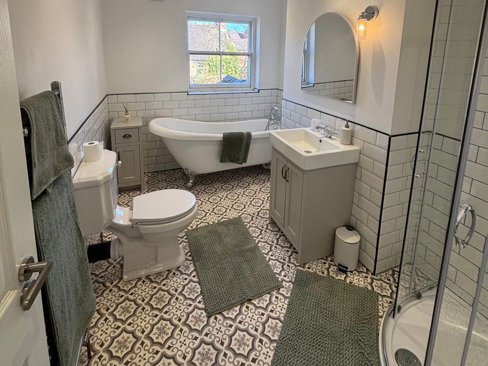 A bathroom with a bathtub, toilet, sink, and shower at Crown Cottage in Belper
