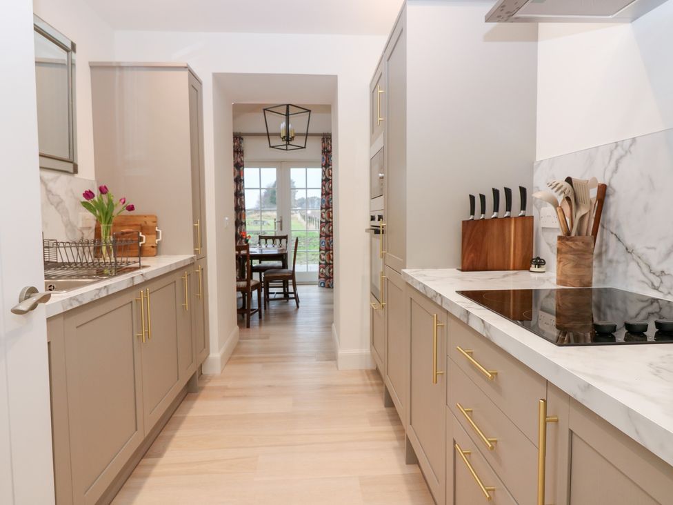 A kitchen with cabinets and a dining area at 4 East Camno Farm Cottages near Meigle
