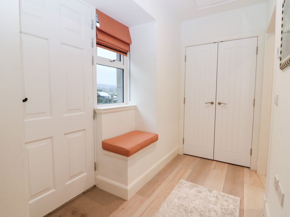 A hallway with a cushioned bench and double doors at 4 East Camno Farm Cottages Near Meigle