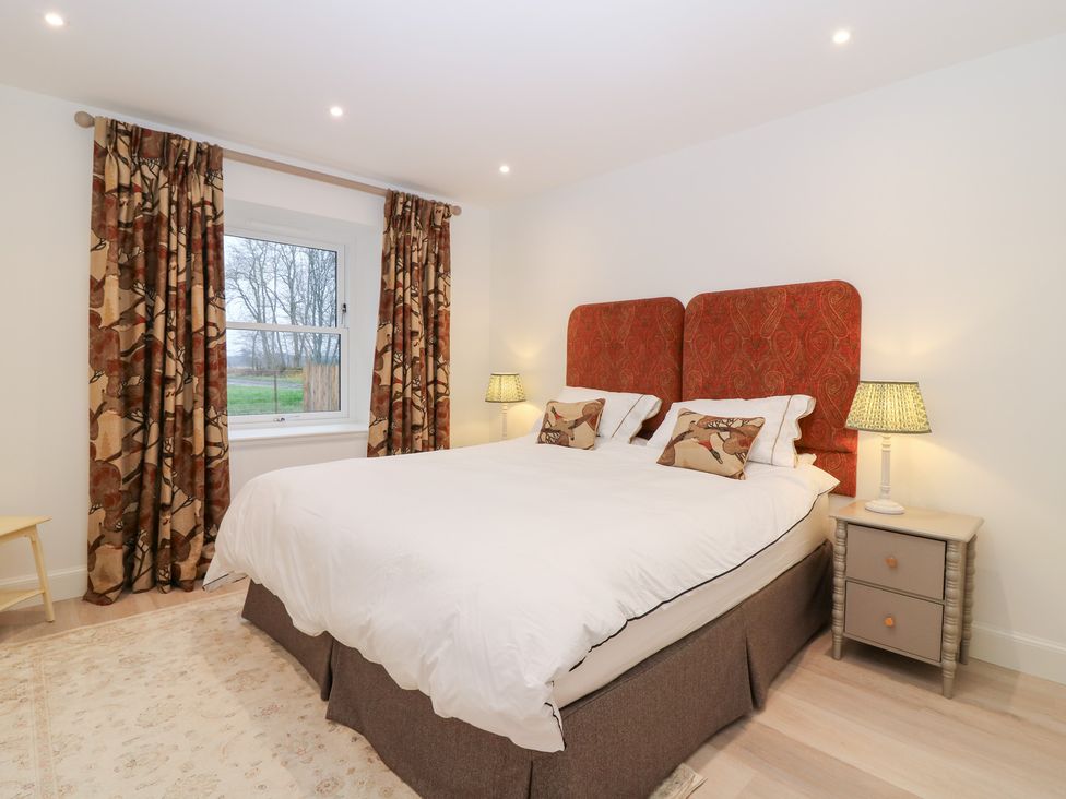 A bedroom with a double bed and bedside table at 4 East Camno Farm Cottages near Meigle