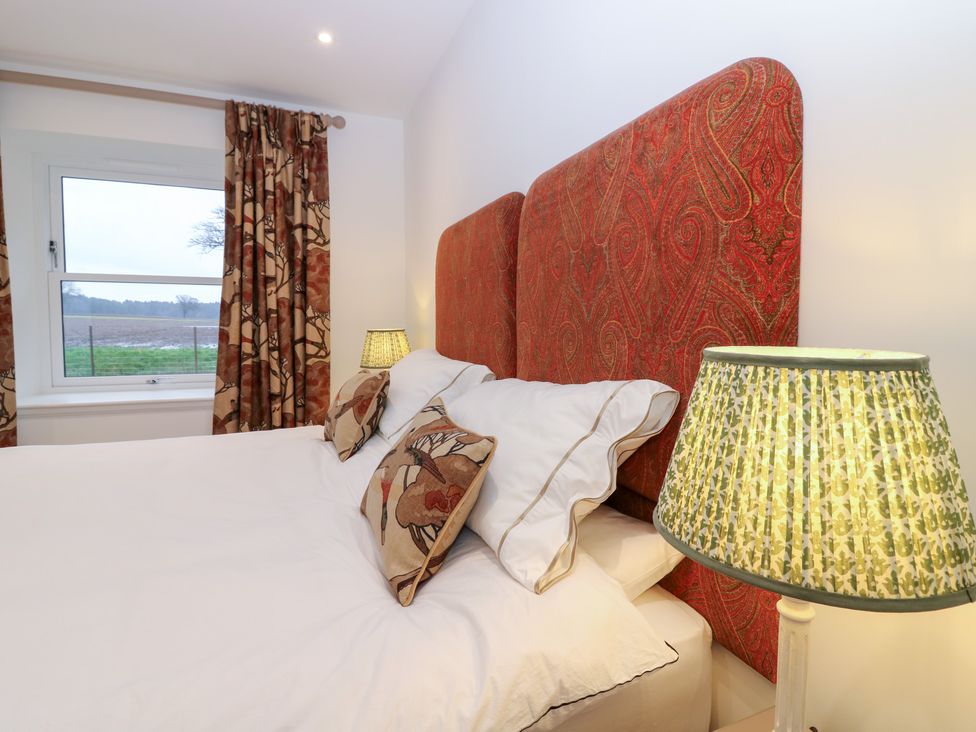 A bedroom with a bed and bedside lamp at 4 East Camno Farm Cottages Near Meigle