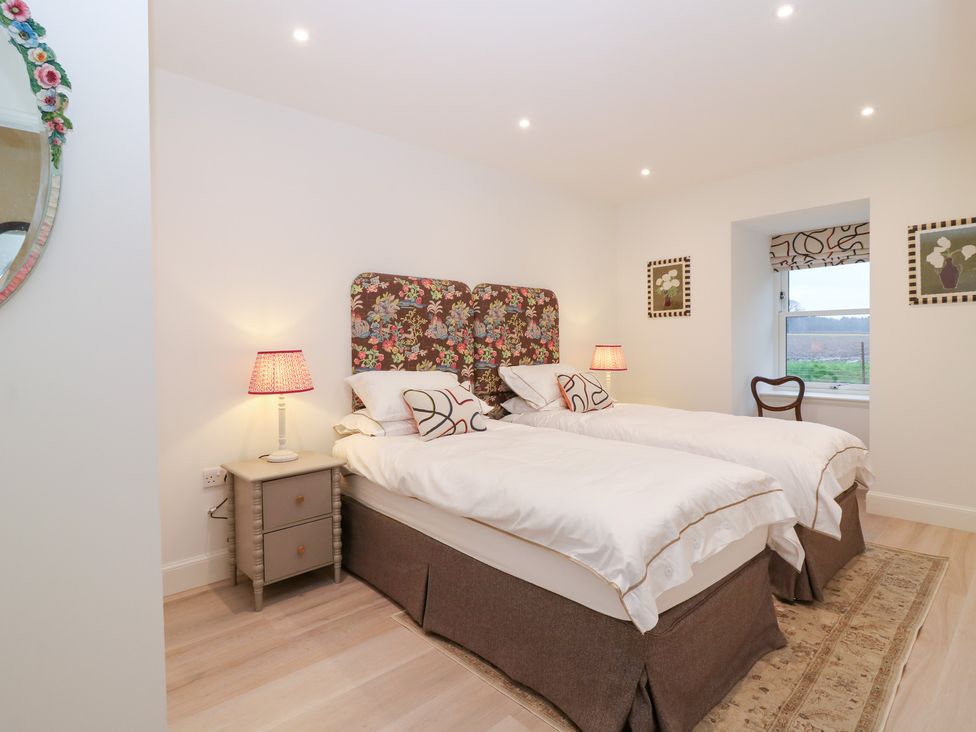 A bedroom with twin beds and a window at 4 East Camno Farm Cottages near Meigle