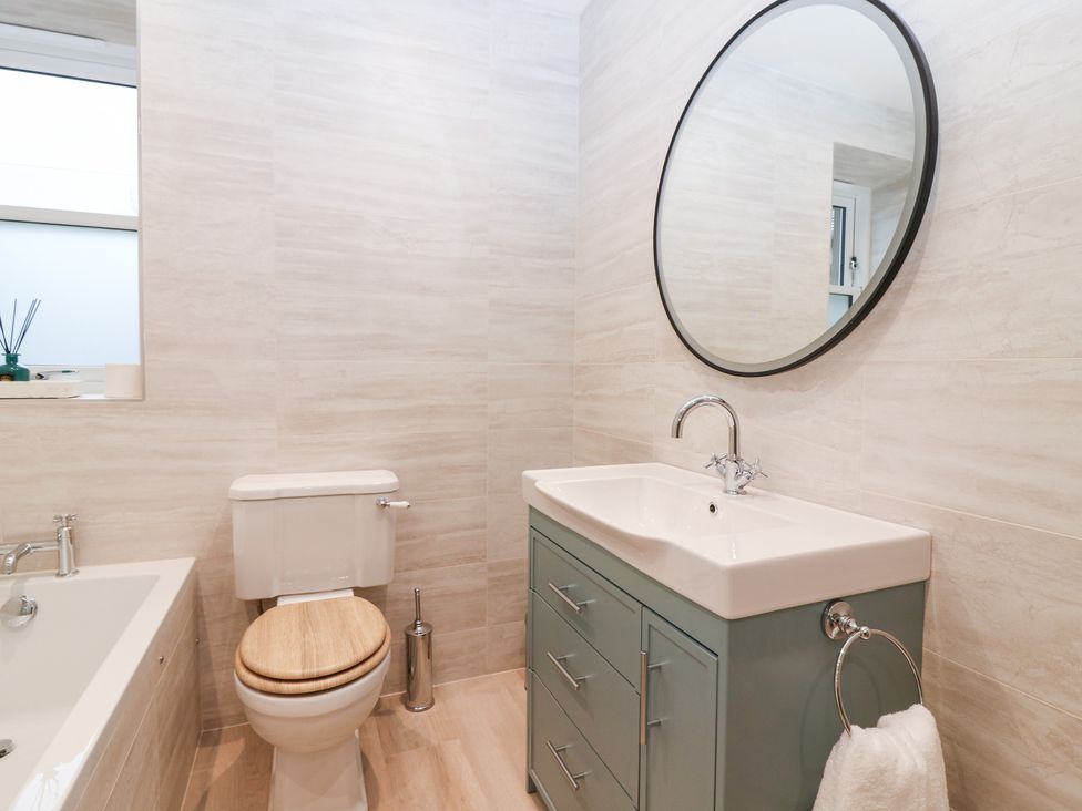 A bathroom with a bathtub, toilet, sink, and mirror at 4 East Camno Farm Cottages near Meigle