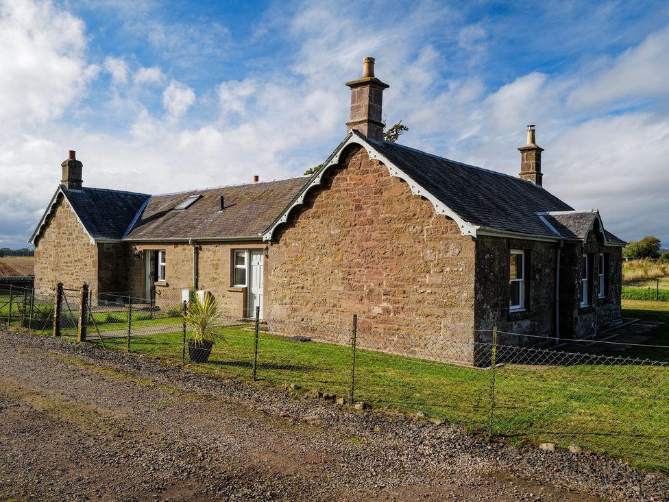 A house with a fence and grass area at East Camno Farm Cottage in Meigle