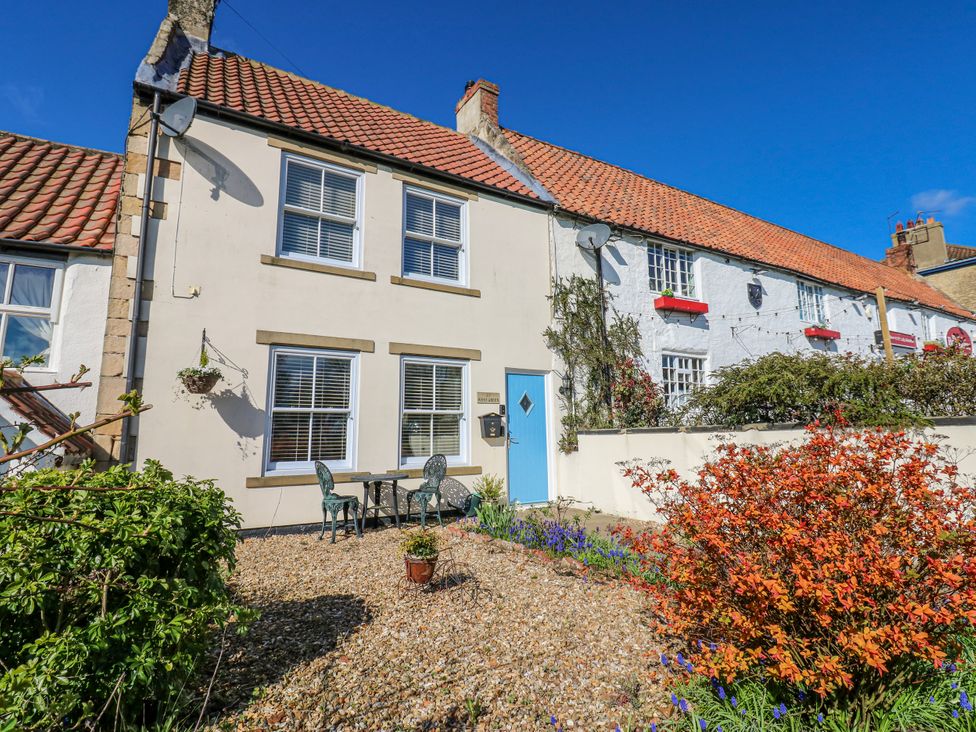 A house with a table and chairs in the garden at 27 West Green
