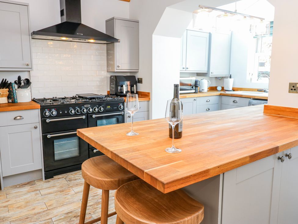 A kitchen with a wooden island and bar stools at 27 West Green