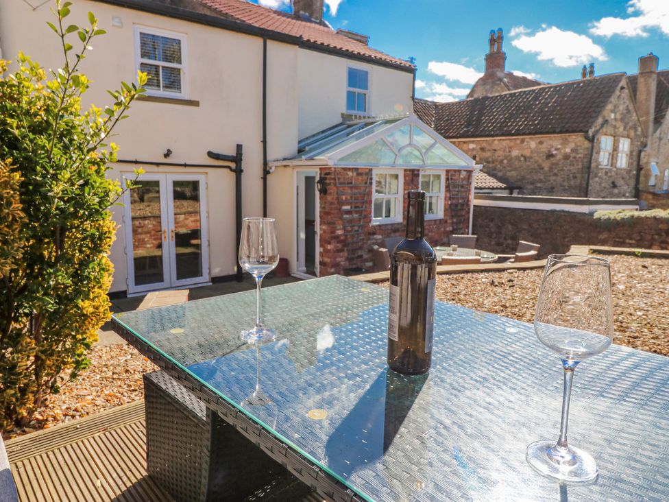 A garden with a table, glass, and bottle at 27 West Green
