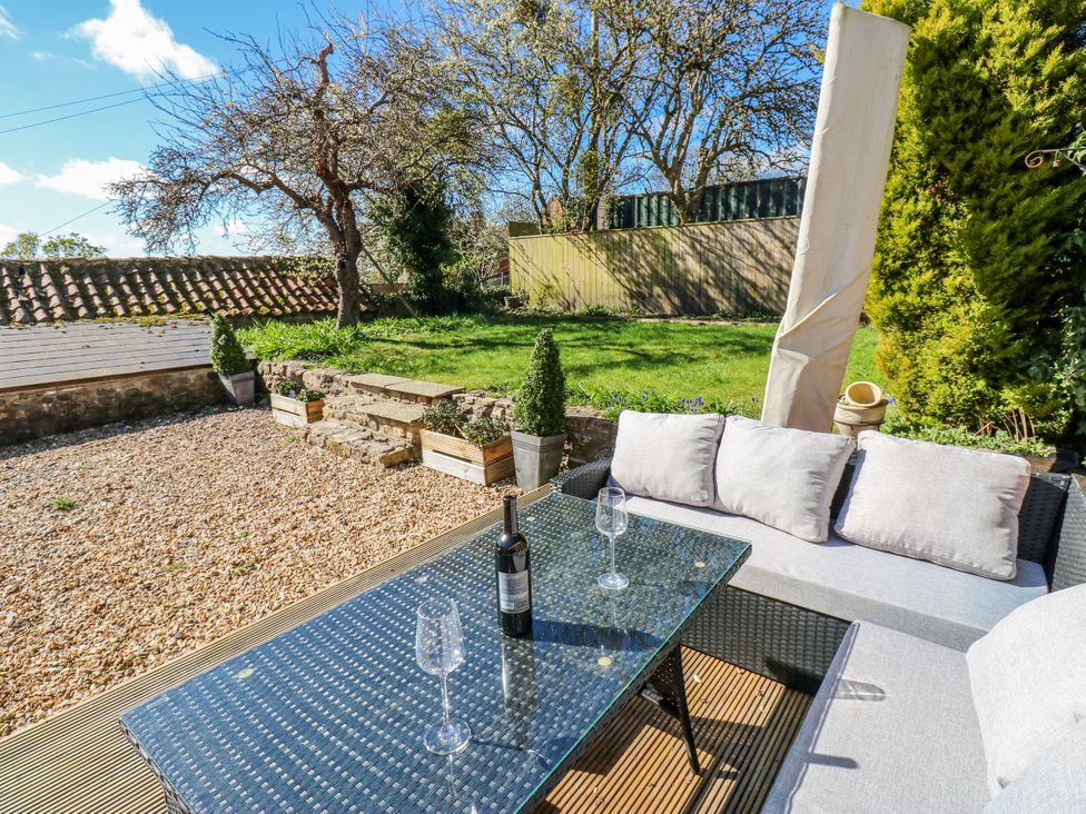 A garden with a sofa and table in front of a grassy area at 27 West Green