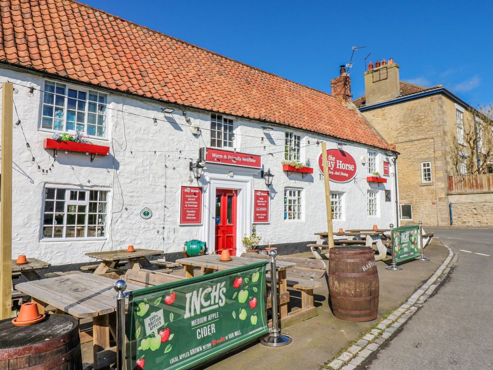 A pub exterior with seating and signs at The Bay Horse