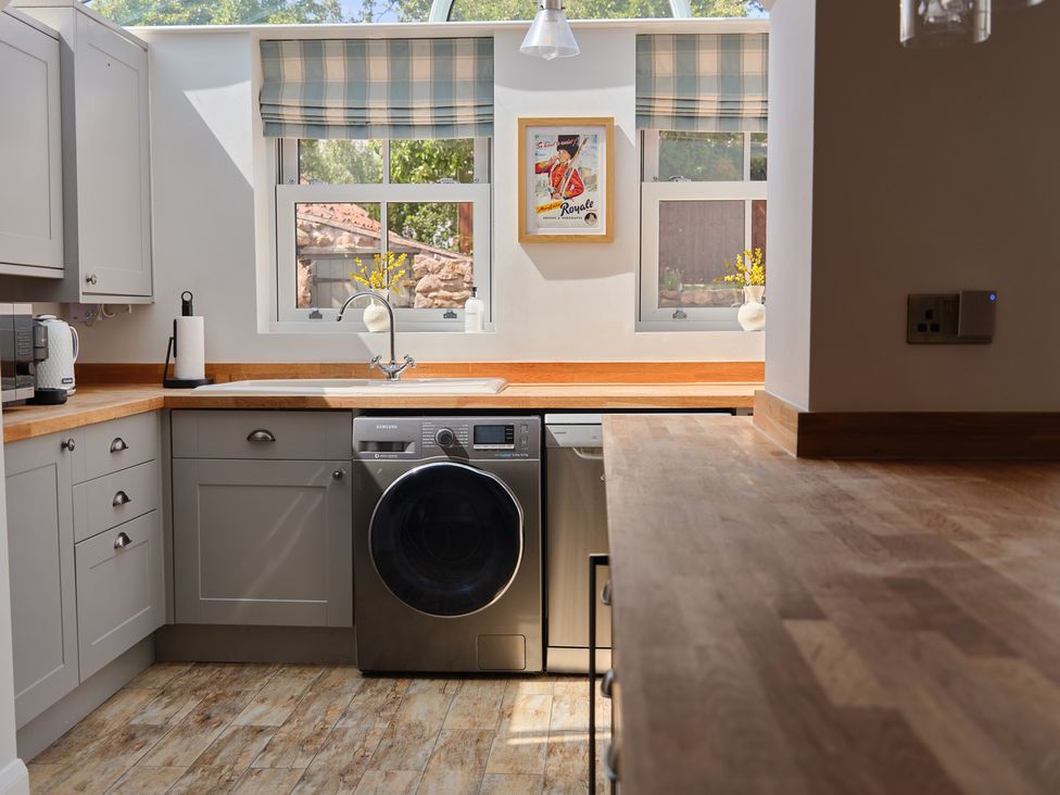 A kitchen with a washing machine and sink at 27 West Green in Heighington