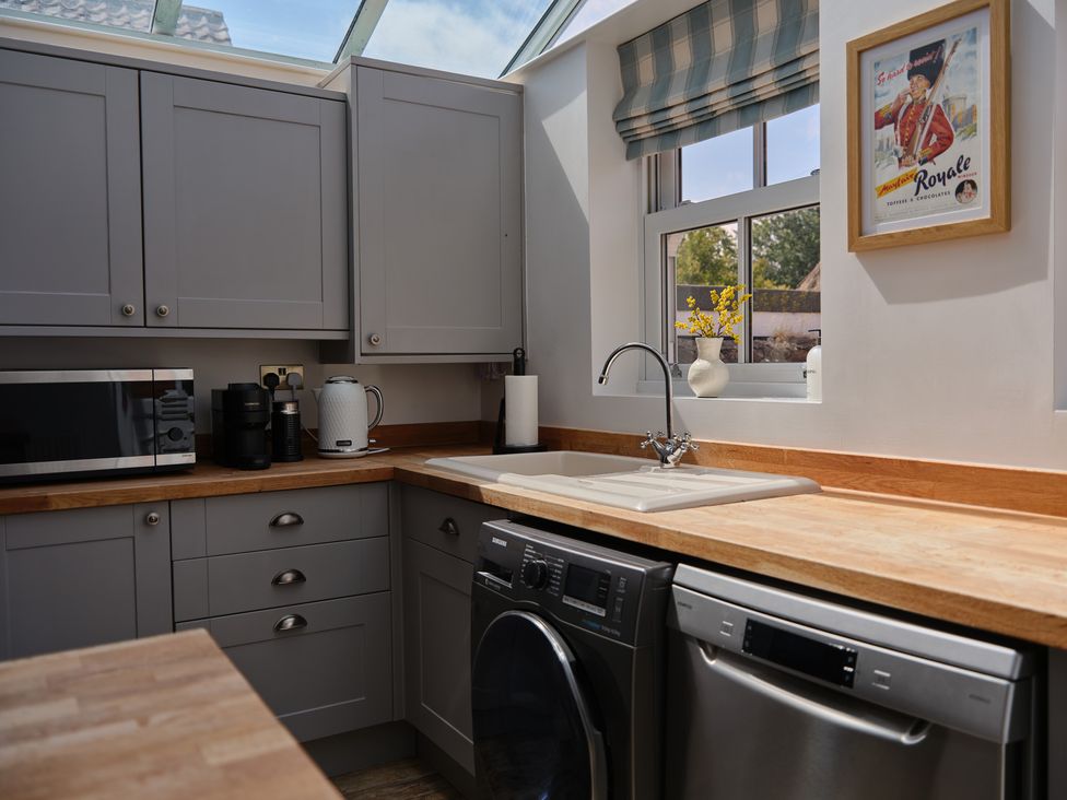 A kitchen with cabinets, appliances, sink and a window at 27 West Green in Heighington