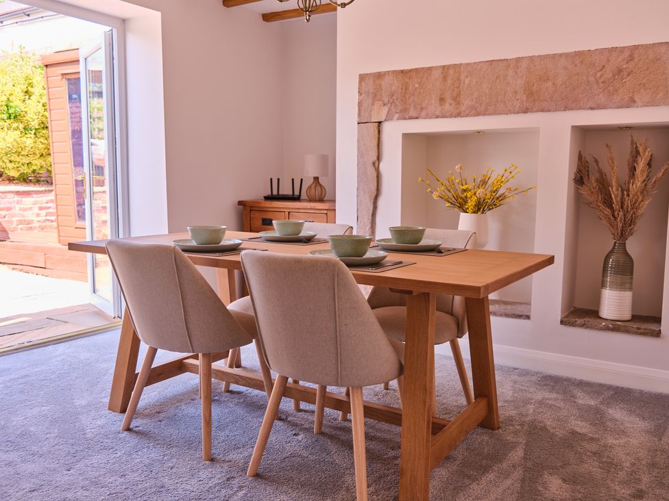 A dining room with a table set and flowers at 27 West Green in Heighington