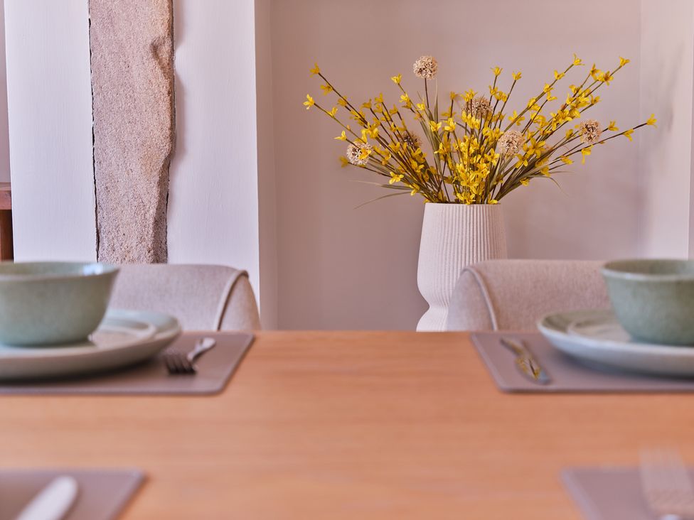 A dining room with a wooden table and floral arrangement at 27 West Green Heighington