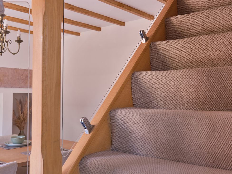 A staircase with a chandelier and dining table at 27 West Green in Heighington