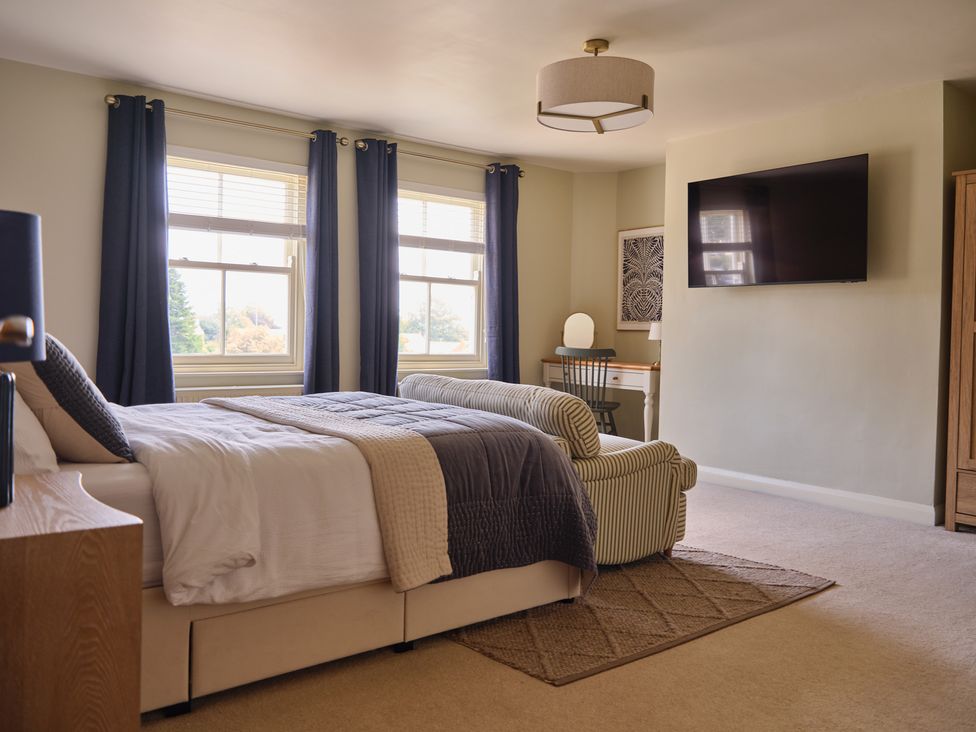 A bedroom with a bed, windows, television and a desk at 27 West Green in Heighington