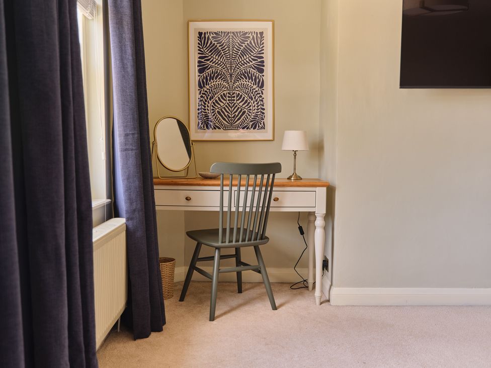 An office with a desk, chair, mirror, lamp, and wall art at 27 West Green Heighington
