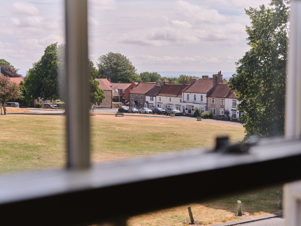 A view of houses and a park area from a window at 27 West Green in Heighington