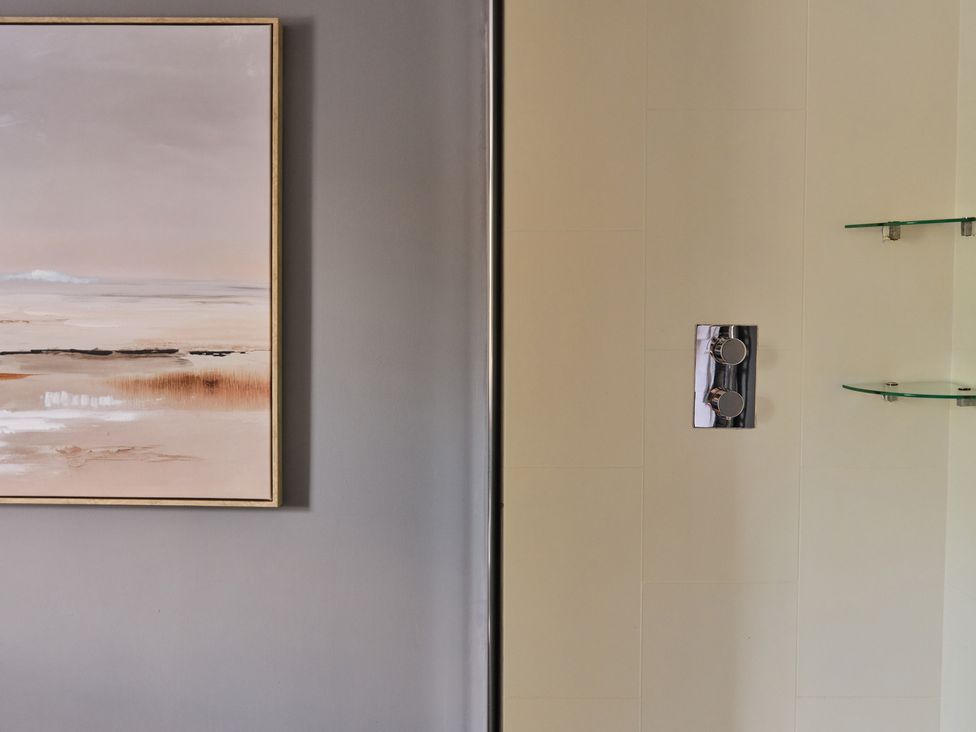 A bathroom with a painting on the wall and a shower control at 27 West Green in Heighington